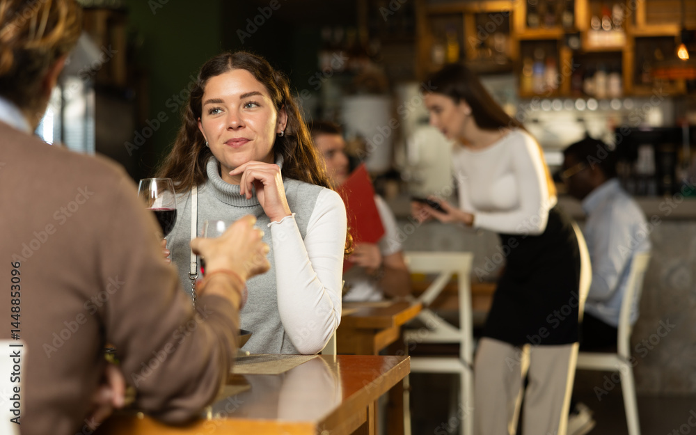 Girl in cafe sits opposite male companion, has nice conversation and discusses news of day. Cozy atmosphere of cafe, meeting place for friends, business partners, colleagues. Girl in cafe sits opposite male companion, has nice conversation and discusses news of day. Cozy atmosphere of cafe, meeting place for friends, business partners, colleagues.