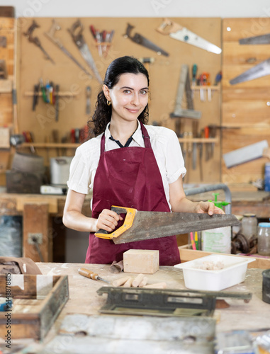 Canvas Print In carpentry workshop, girl master performs work, is engaged in production of wooden decorative household products, learn to work with piece of wood