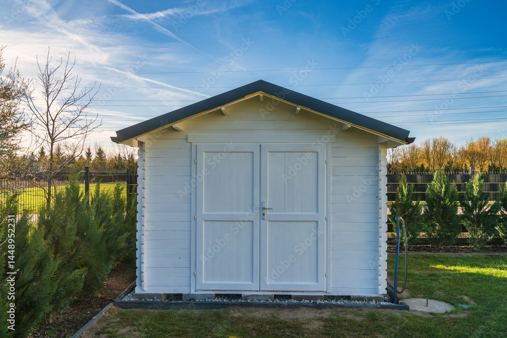 Wooden painted in white shed in the garden under clear blue sky