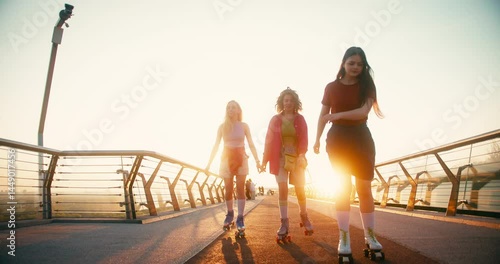 Multicultural Women in Casual Clothes Riding Roller Skates. Fit Beautiful Friends Moving and Spinning Around while Entertaining during Sunrise. Fitness Youth Culture Diversity