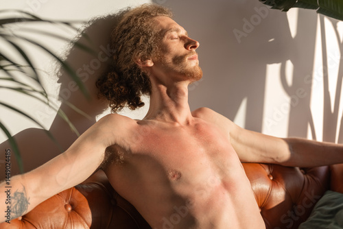 Man with sunburn resting on couch at home