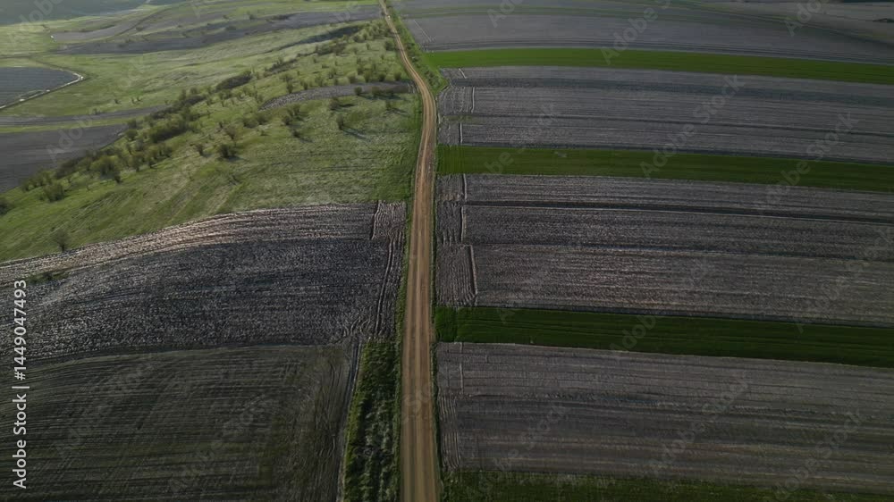 Flying over gravel road that divides land plots prepped for agricultural purposes