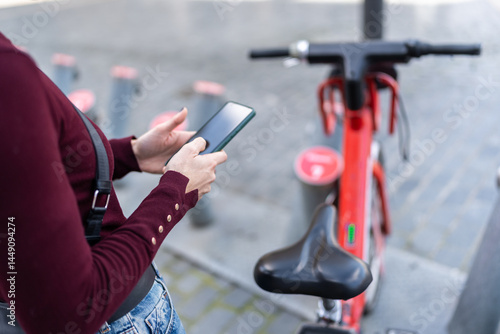 Woman using smartphone unlocking shared electric bicycle in Bilbao