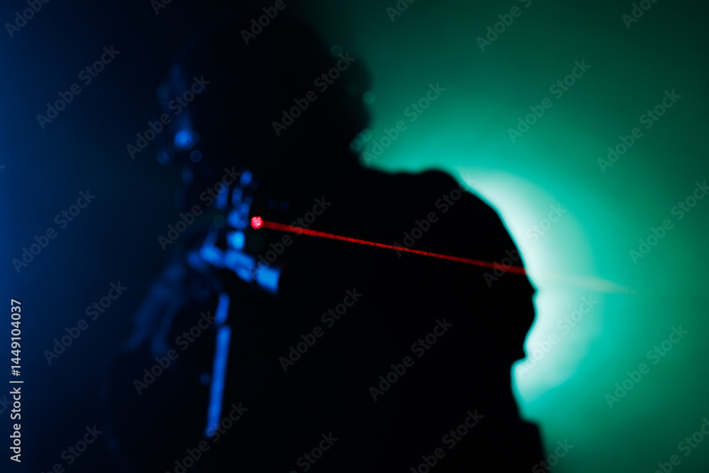 Fototapeta premium Silhouette of Person Aiming with Laser Sight Amid Dramatic Background