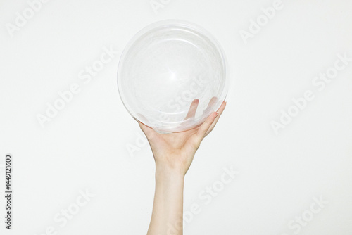 Hand holding clear geometric plastic rounded bubble with flash