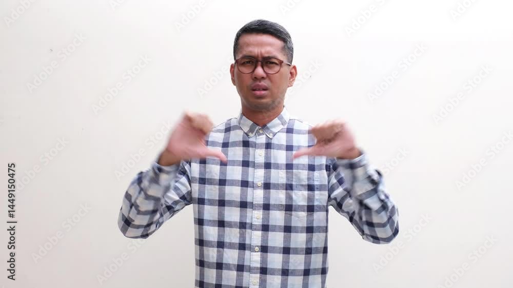 Adult Asian man showing disappointed expression and give thumbs down Adult Asian man showing disappointed expression and give thumbs down