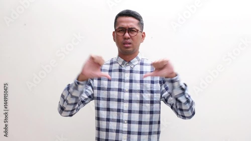 Adult Asian man showing disappointed expression and give thumbs down