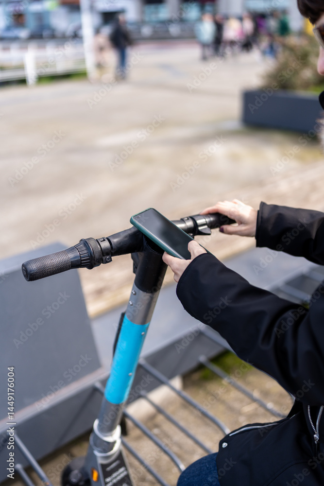 Woman unlocking electric scooter with mobile phone in Asturias, Spain Woman unlocking electric scooter with mobile phone in Asturias, Spain