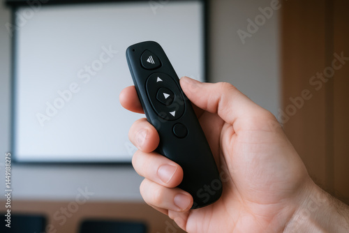 Wallpaper Mural Hand holding black remote control with mechanical buttons used for consulting presentations in modern office setting Torontodigital.ca