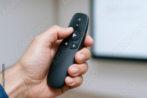 Wallpaper Mural Hand holding black remote control with mechanical buttons used for consulting presentations or media playback in modern setting Torontodigital.ca