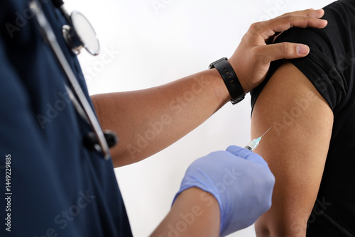 Close-up of medical nurse being vaccinated in studio by doctor. Medic uses syringe with needle to administer vaccination injection to arm of asian healthcare specialist.