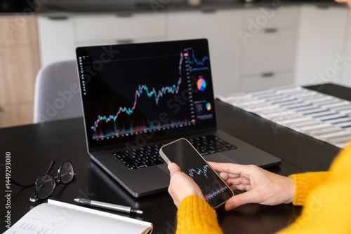 Investor analyzing stock chart using laptop and phone