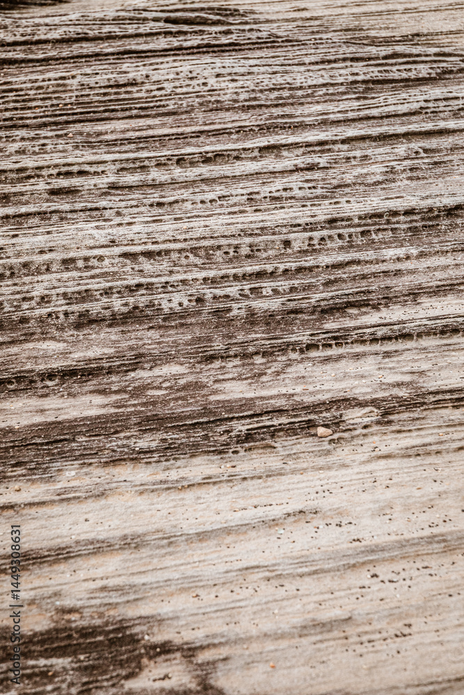 Detailed rock surface textures along sandy area. Detailed rock surface textures along sandy area.