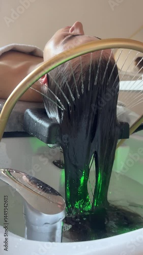 Close-up of a woman receiving a head massage during a Japanese head spa treatment with water flowing from a special hair washing tool, focusing on the scalp relaxation and beauty therapy