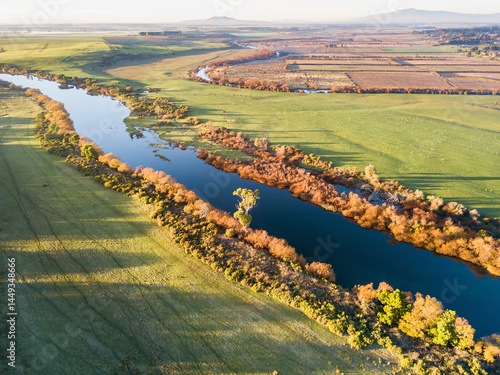 Inland river lined with trees cover in golden leaves 