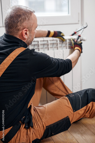 Obraz na płótnie Central heating mechanic and handyman fixing home radiator, gas crisis and seasonal issues. w salonie