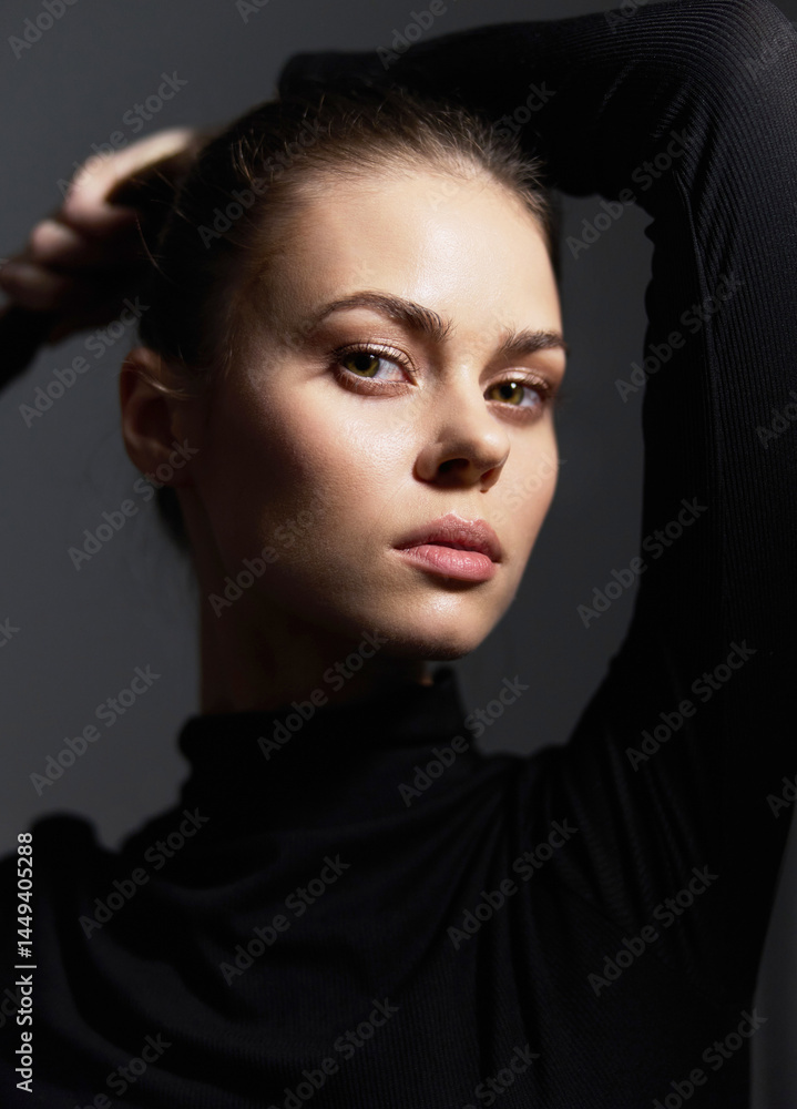 Stylish young woman with a confident expression, wearing a black turtleneck, posing against a dark background with soft lighting. Fashion and beauty concept. Stylish young woman with a confident expression, wearing a black turtleneck, posing against a dark background with soft lighting. Fashion and beauty concept.