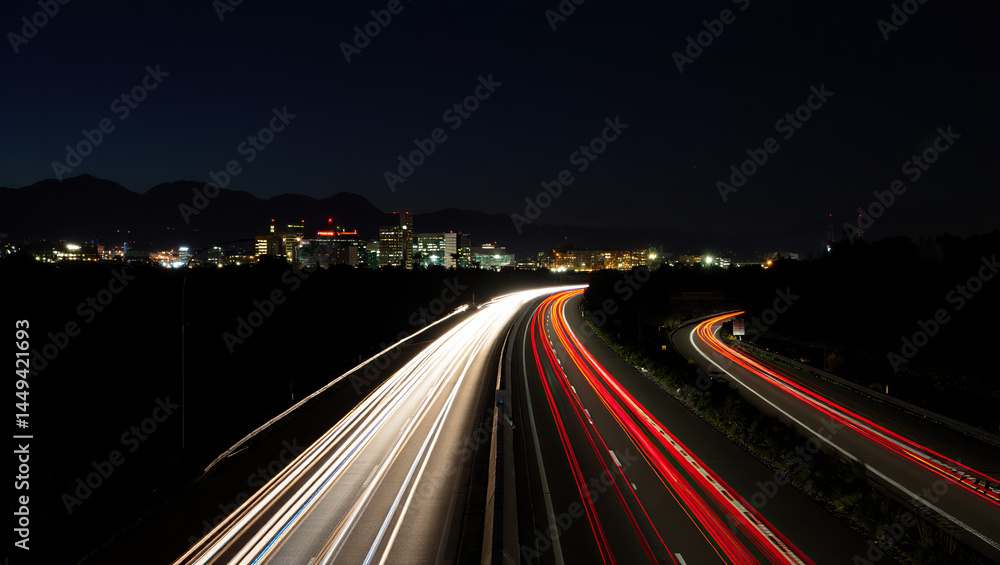 Glowing speed light trails streak down a highway, leading into a city, set against dark mountain skies, capturing dynamic movement and night energy. Glowing speed light trails streak down a highway, leading into a city, set against dark mountain skies, capturing dynamic movement and night energy.