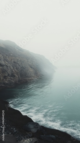 Misty Coastal Scenery: Dramatic Fog Over Dark Volcanic Beach
