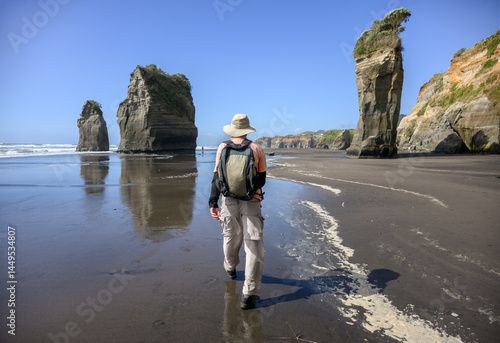Tourists walking towards Three Sisters rock formation. Tongaporutu beach. Taranaki. New Zealand.