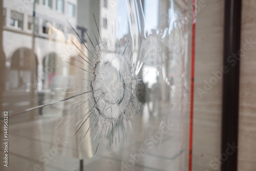 Foto Close-up of cracked storefront window with central impact point, surrounded by red caution tape