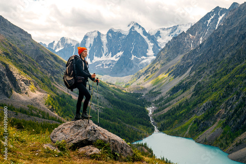 A tourist girl with a backpack stands on an observation deck overlooking Lake Shavlinsky in Altai
