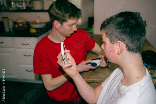 teen checking his haircut given by brother 