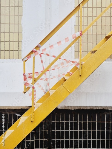 Yellow staircase with caution tape blocking access in urban setting
