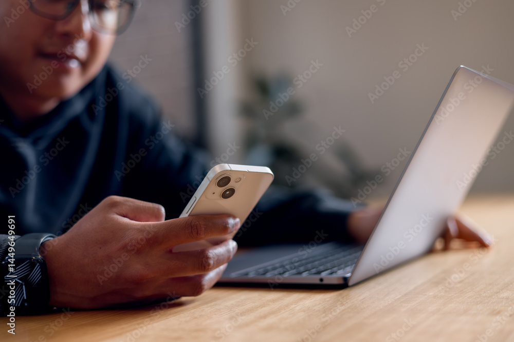 businessman using a smartphone while sitting at a desk with a laptop in a modern office environment.using artificial intelligence smart apps businessman using a smartphone while sitting at a desk with a laptop in a modern office environment.using artificial intelligence smart apps