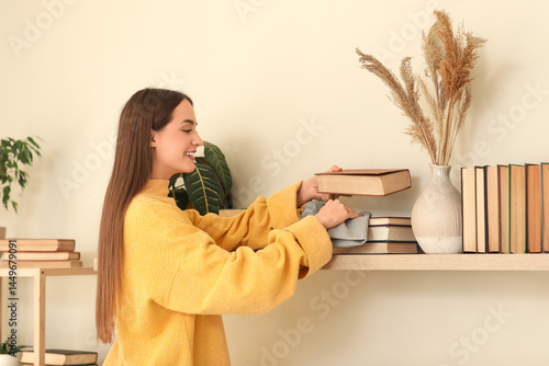 Young woman wiping dust fro...
