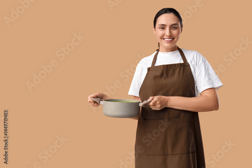 Young woman in apron holdin...