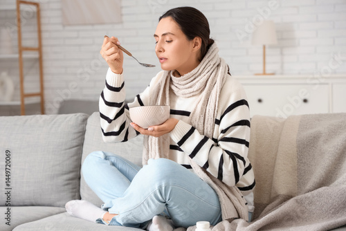 Sick young woman eating sou...