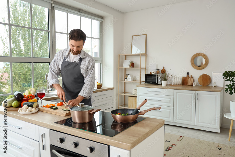 Handsome bearded man cutting vegetables in kitchen Handsome bearded man cutting vegetables in kitchen