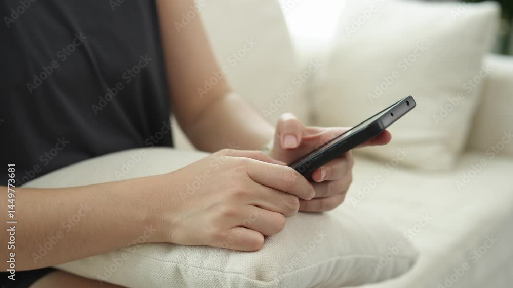 Woman using smartphone while sitting on couch, focused on screen, relaxed indoor atmosphere, modern living room, casual lifestyle concept, close-up view Woman using smartphone while sitting on couch, focused on screen, relaxed indoor atmosphere, modern living room, casual lifestyle concept, close-up view