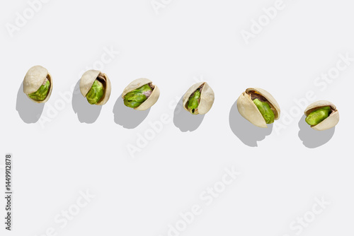 Obraz na płótnie Pistachio nuts isolated on white background. Top view. Roasted green pistachios in open shells on white background with shadow. w salonie