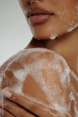 Light soap suds covering a woman's shoulder, smooth natural skin texture, close-up.