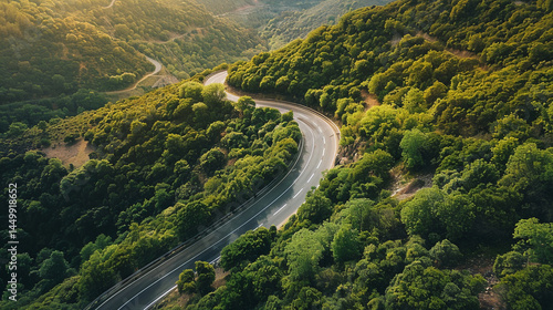 A serpentine road carves its path through a lush green valley, sunlight dappling the hillsides and hinting at the scenic journey ahead through the majestic landscape.