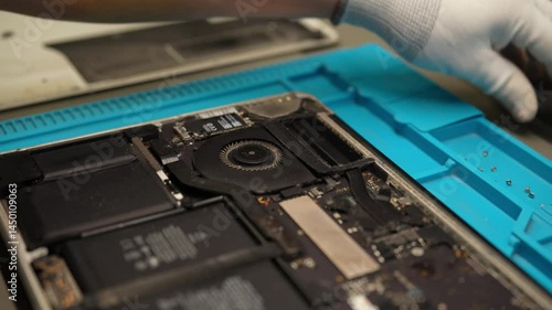 Skilled technician repairing laptop motherboard, disassembling electronic components with screwdriver in professional workshop, close-up. Concept of computer hardware, repairing, upgrade, technology.