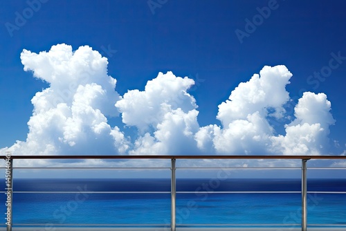 Ocean view from a ship's deck with fluffy white clouds against a vibrant blue sky.  A railing divides the upper sky from the lower sea