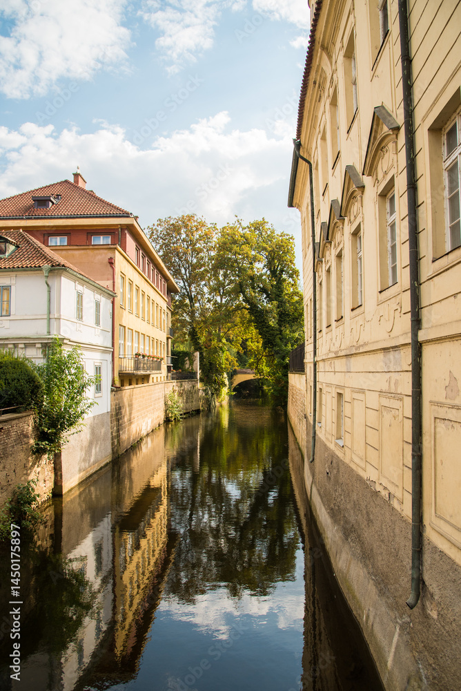 Fototapeta premium Canal between historic buildings with reflections and blue sky