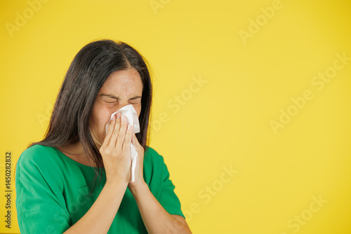 Woman sneezing into tissue, representing allergy, common cold and seasonal illness