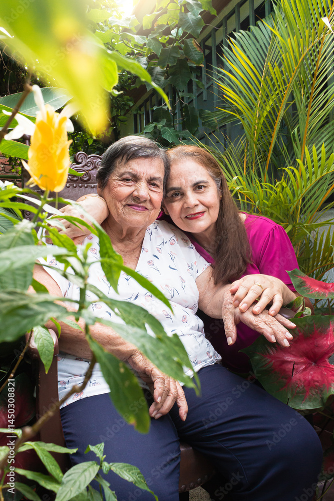 Obraz premium Portrait of an adult daughter hugging her elderly mother in a garden in Yaguara, Huila, Colombia. Concept of family and colombian people