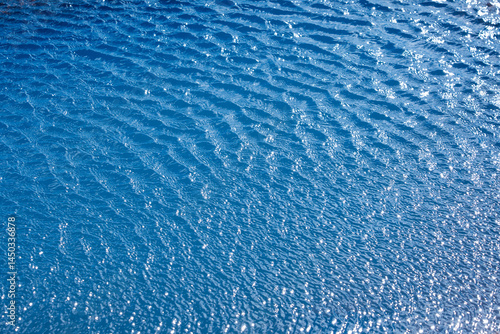 Fotografie Rippling blue water surface reflecting sunlight on a clear day at a tropical bea