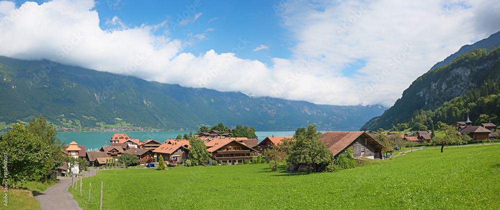 way down to tourist resort Iseltwald, lake Brienzersee. Clouds over mountains. swiss alps