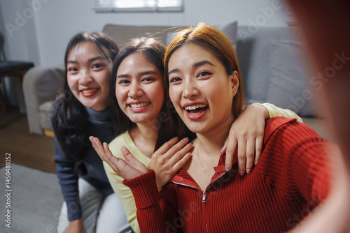 Bild auf Leinwand Three young women are smiling and taking a selfie together in their living room,