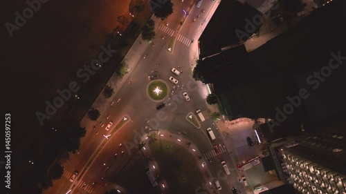 City intersection at night showing traffic flow and bright streetlights