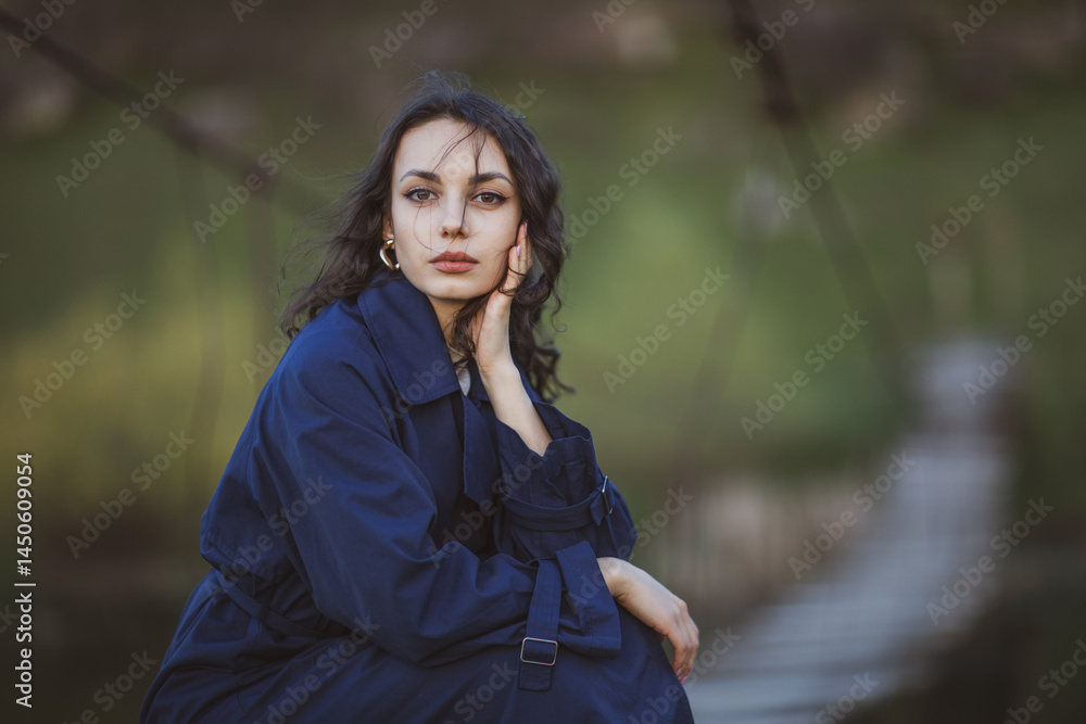 beautiful brunette european girl in blue trench coat at nature. Young lady with beautiful face and lips.