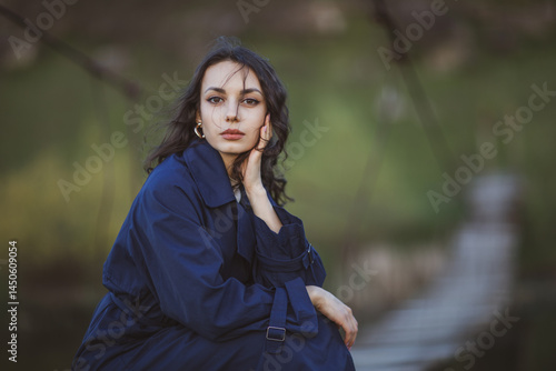 Obraz na płótnie beautiful brunette european girl in blue trench coat at nature. Young lady with beautiful face and lips. w salonie