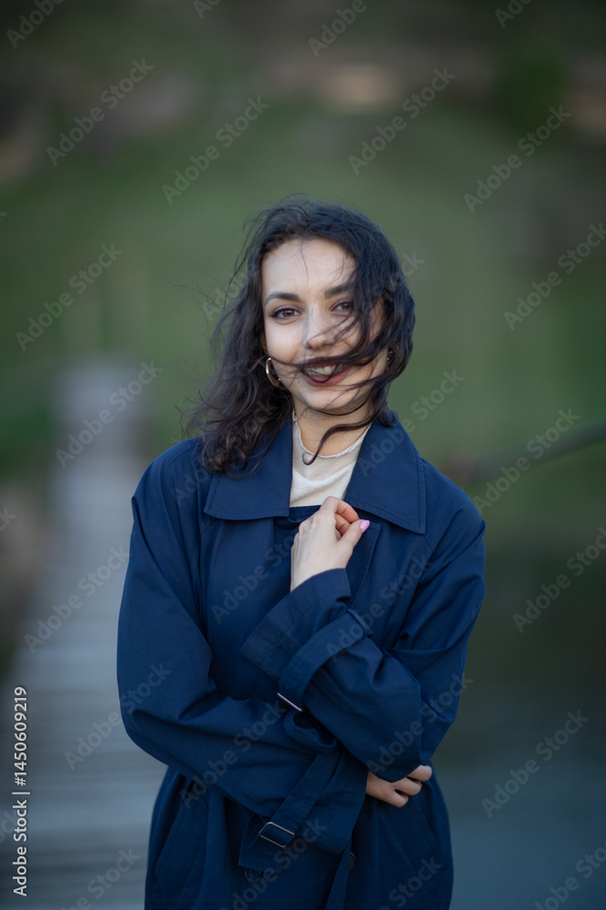 beautiful brunette european girl in blue trench coat at nature. Young lady with beautiful face and lips.