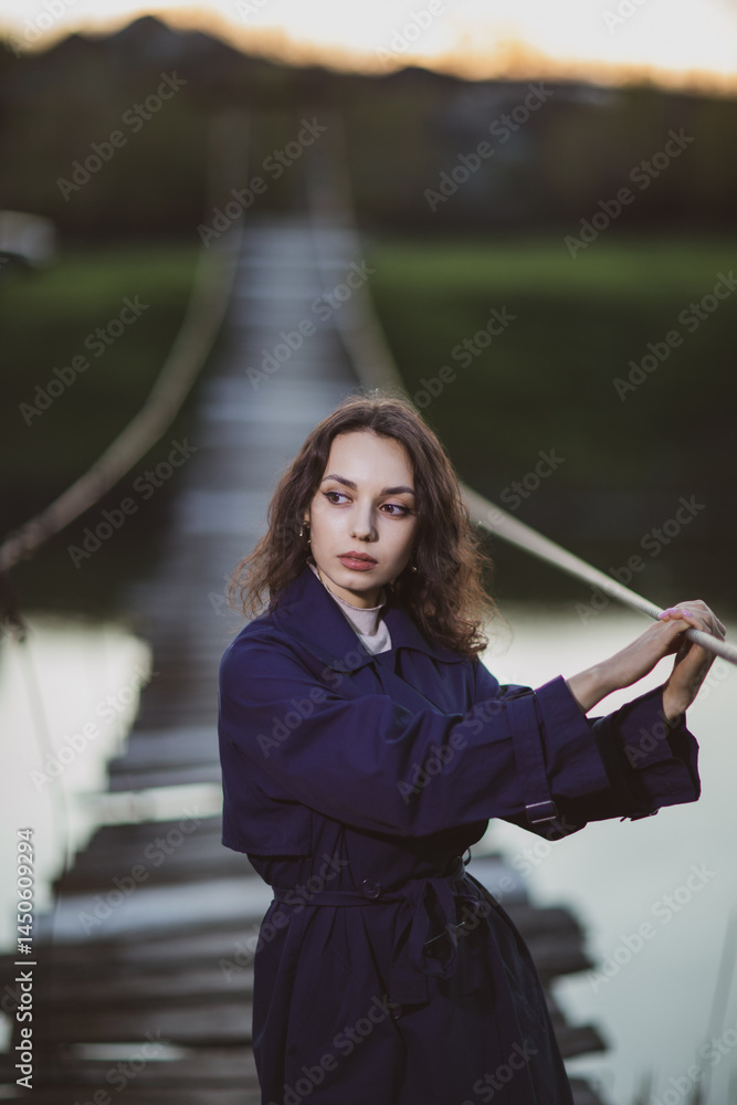 beautiful brunette european girl in blue trench coat at nature. Young lady with beautiful face and lips.